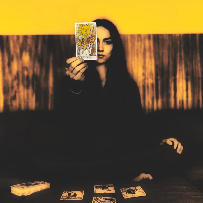 Eine Frau welche eine Tarotkarte mit der Sonne in die Kamera hält. Symbolbild für einen Fachbeitrag über die spirituelle Bedeutung der Sonne.