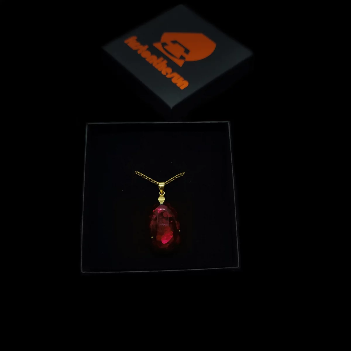 Orgonit Amulett "Blut des Berges" mit firstonthesun Karton. Die Kette des Orgoniten ist goldfarben.