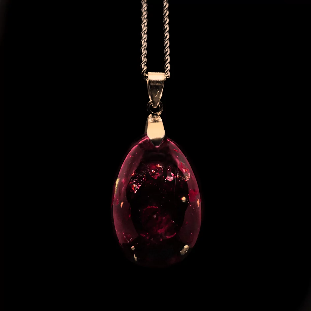 Orgonit Schmuck Anhänger aus Edelsteinen mit Rubin in roter Farbe mit goldenem Anhänger und goldener Kette.