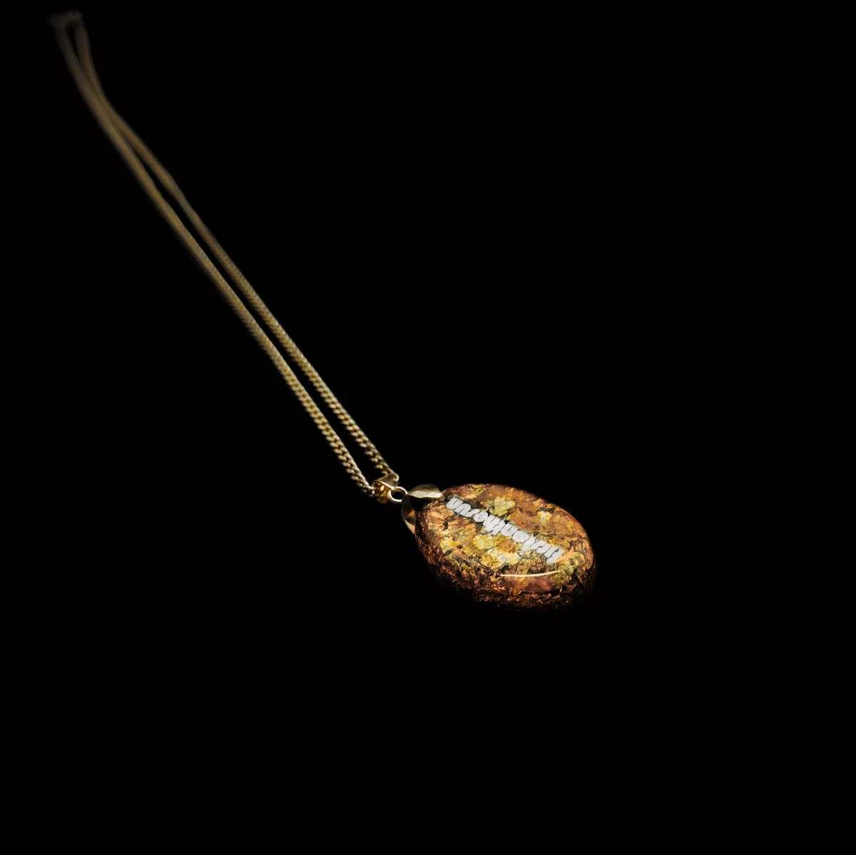 Produktansicht der mit Goldflocken besetzten Rückseite eines Rosenquarz Orgonit Anhängers.